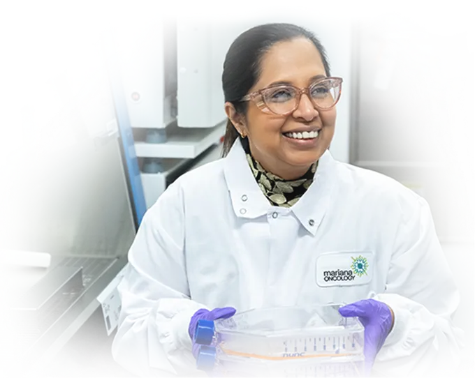 Mariana Oncology scientist smiling and holding a cell culture flask in the lab